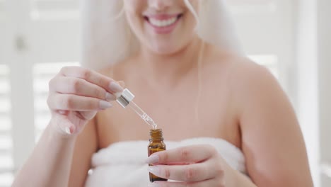 happy caucasian plus size woman with bathrobe preparing oil in bathroom in slow motion