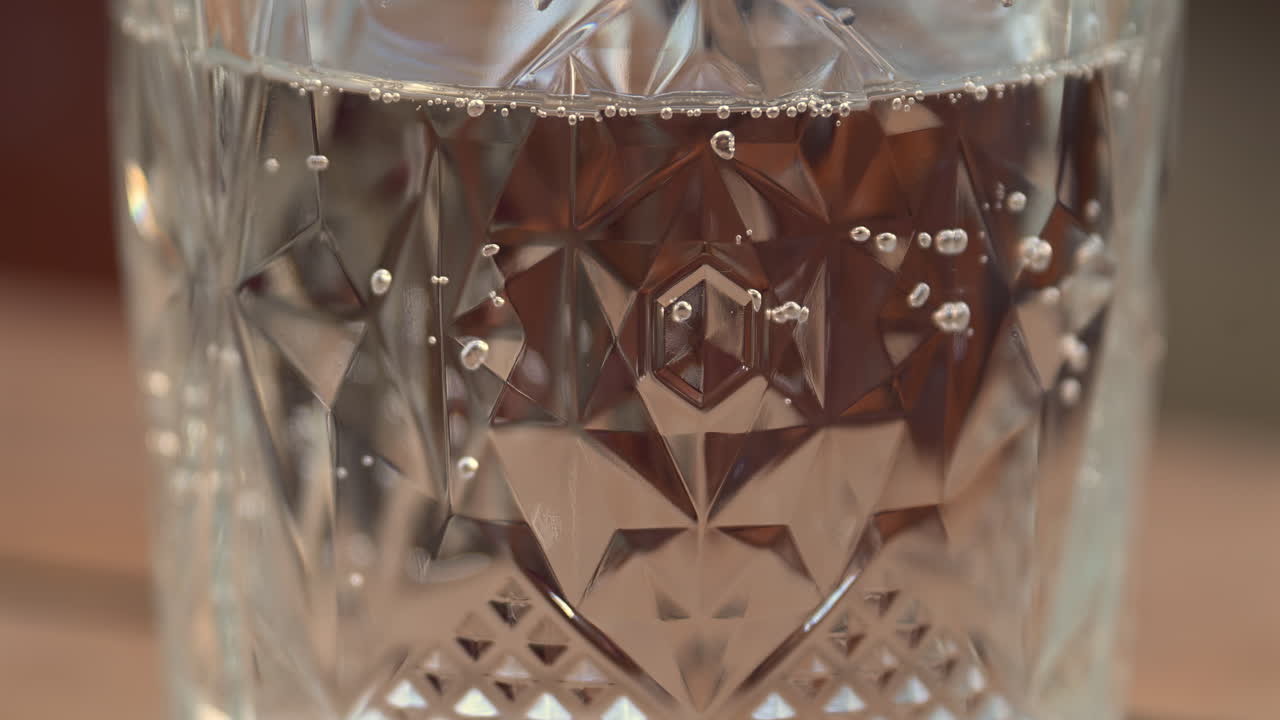 Close up of bubbles moving up in a glass of sparkling water on a wooden table