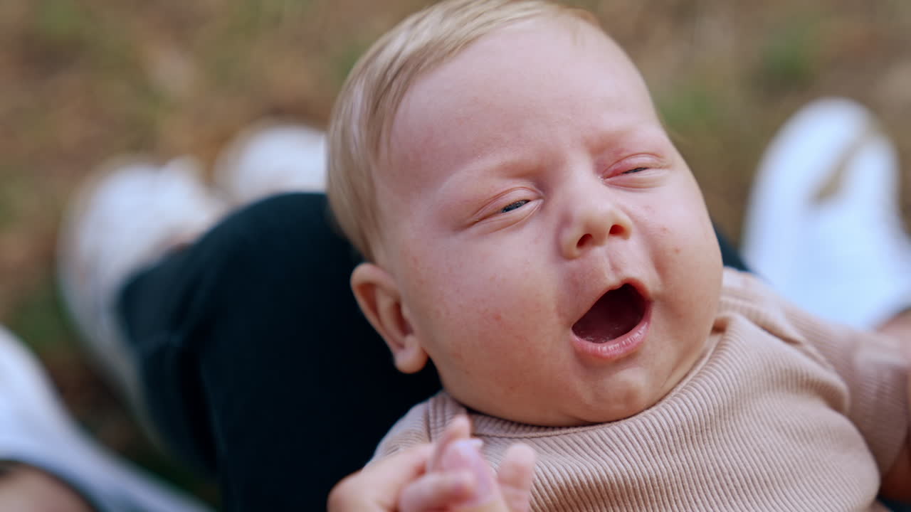 Lovely cute baby smiling adorable from mom's touch. Portrait of a Caucasian blonde infant close up.