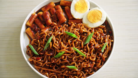 jjajang rabokki - fideos instantáneos coreanos o ramyeon con pastel de arroz coreano o tteokbokki y huevo en salsa de frijol negro - estilo de comida coreana