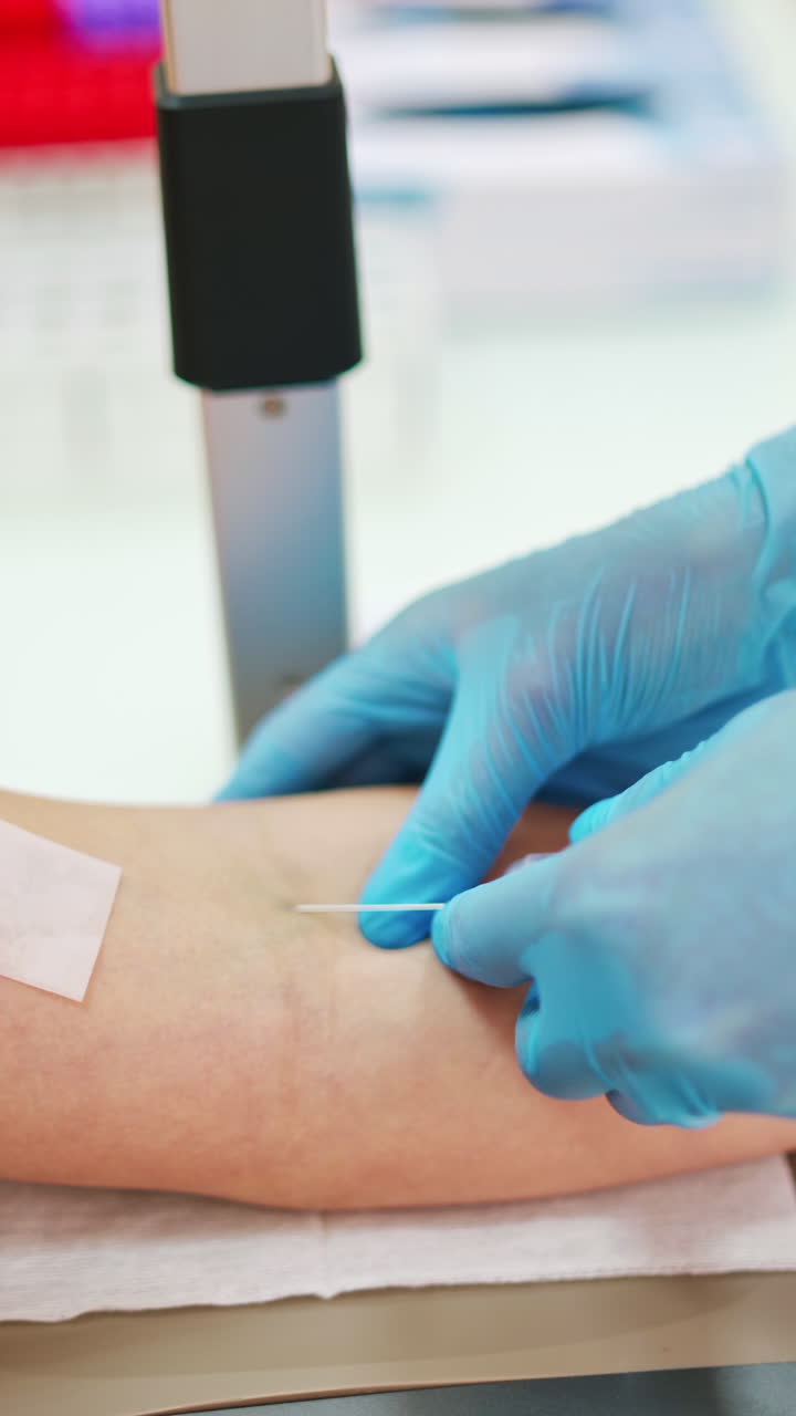 Medical assistant taking a blood sample from vein. Hands of doctor inject a syringe into a vein to a female patient. Close-up. Vertical video