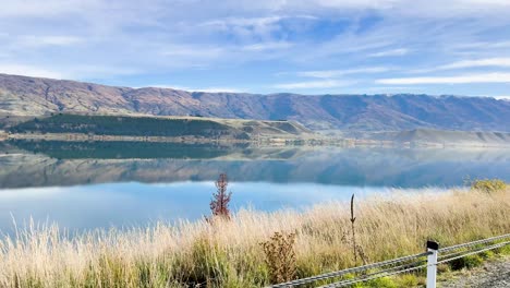 a serene drive by a tranquil lake with mountain reflections under a clear sky in queenstown, new zealand