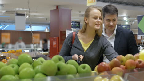 happy young couple buying apples in the supermarket