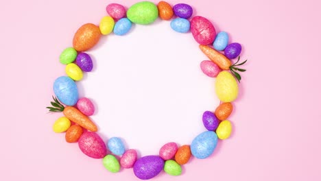paper card note surrounded by vibrant easter eggs on pastel pink background. stop motion