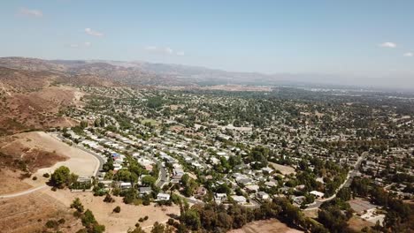 drone establishing shot of hidden hills town near los angeles during sunny day. sandy desert hills beside upper class housing area. wide shot.