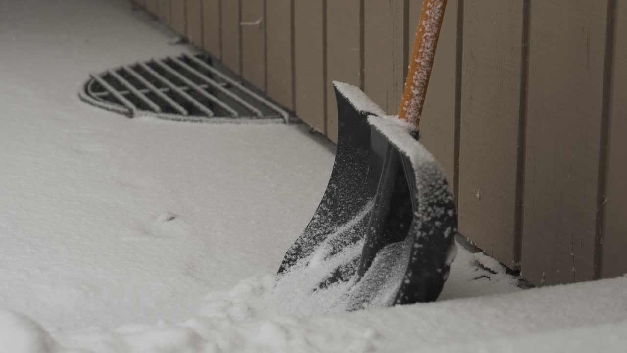 Slow motion snowfall with a plastic shovel in frame