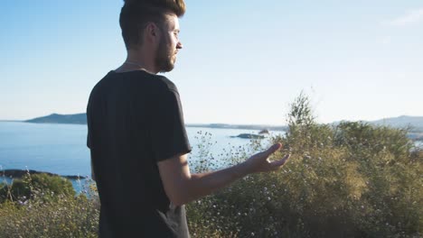 man throwing stone with a powerful throw into wilderness in slowmotion with a view on the ocean