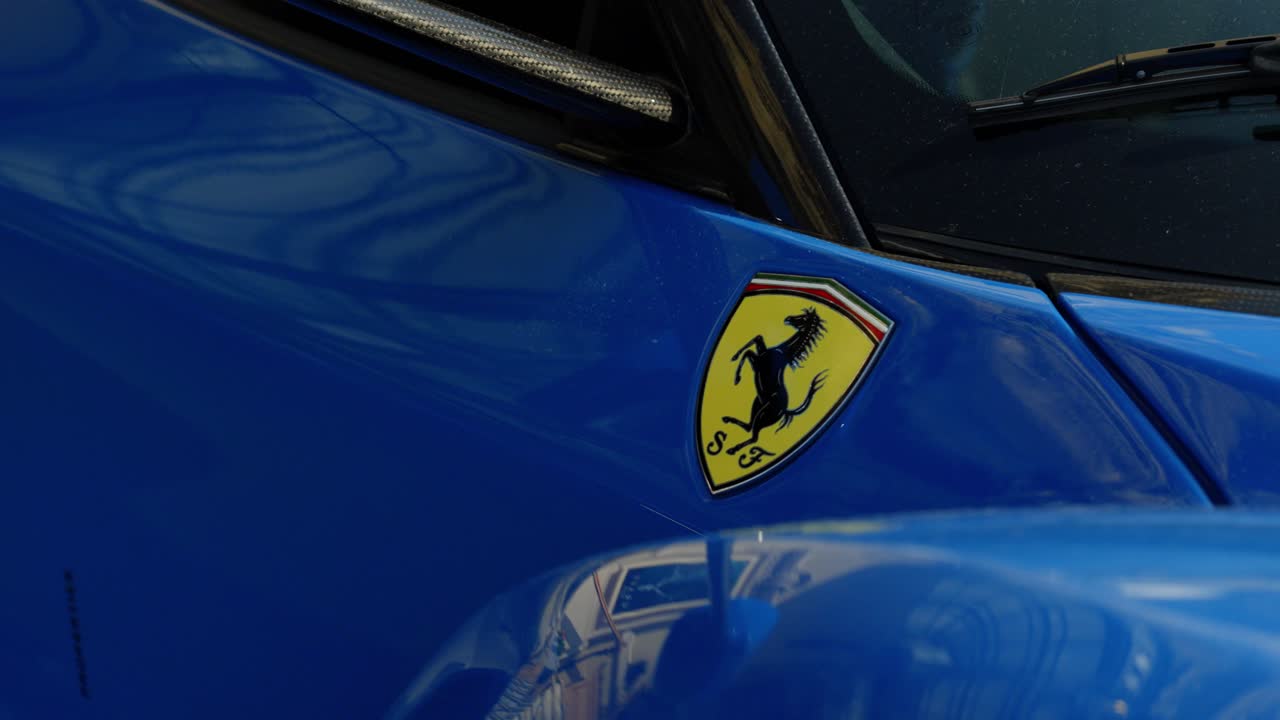 slow orbiting shot revealing a Ferrari bade on the wing of a blue supercar
