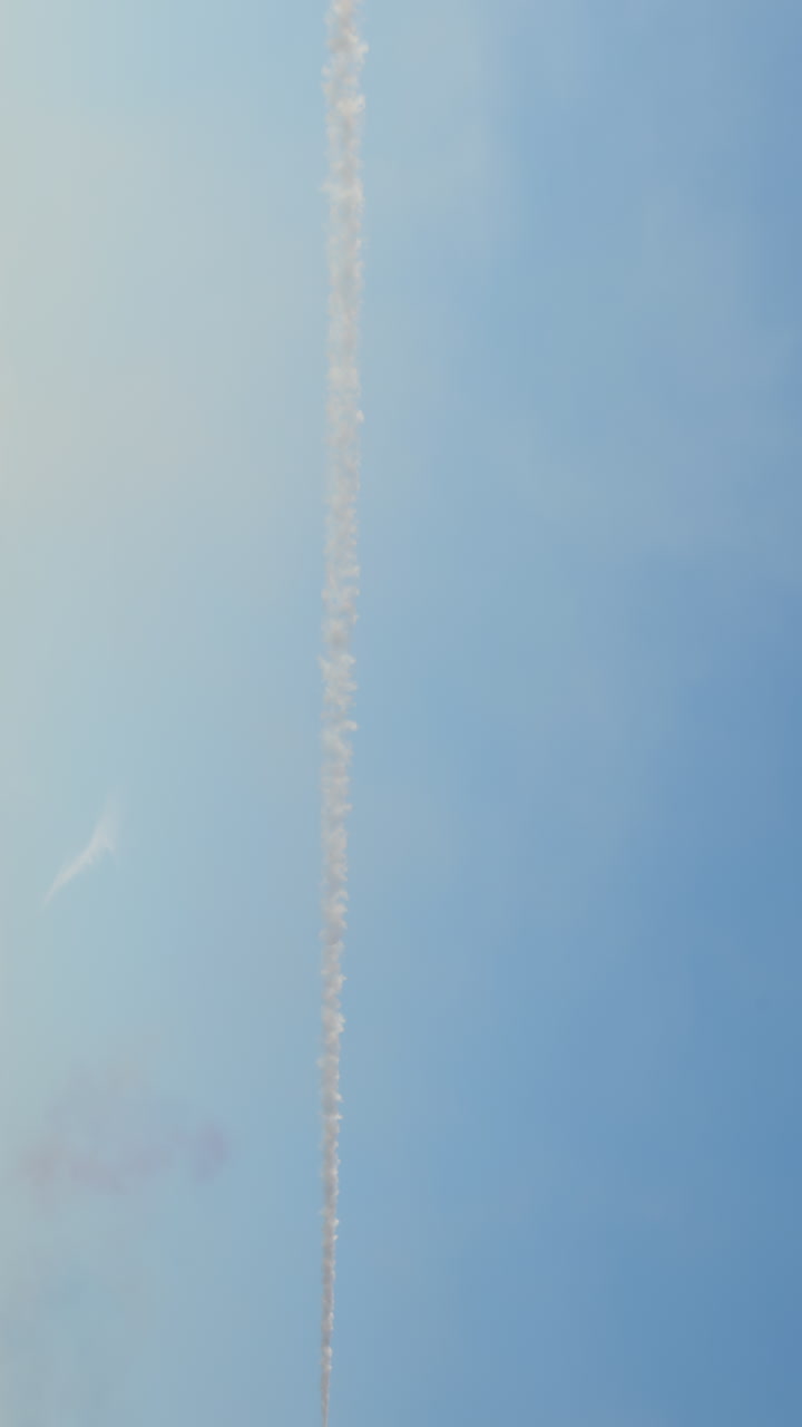 Aeroplano rosso che esegue acrobazie aeree con scia di fumo bianco nel cielo blu