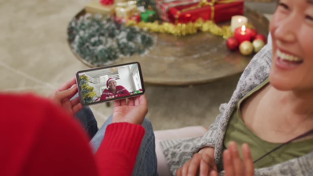 스크린 에 있는 여자 와 함께 크리스마스 비디오 통화 를 하기 위해 스마트폰 을 사용하는 웃는 아시아 커플