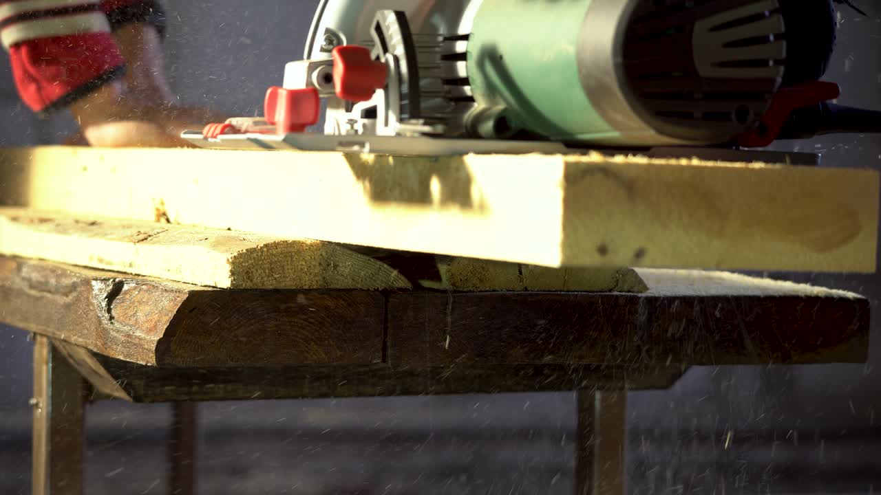 рабочий плотник режет деревянную доску с помощью ручной круговой пилы