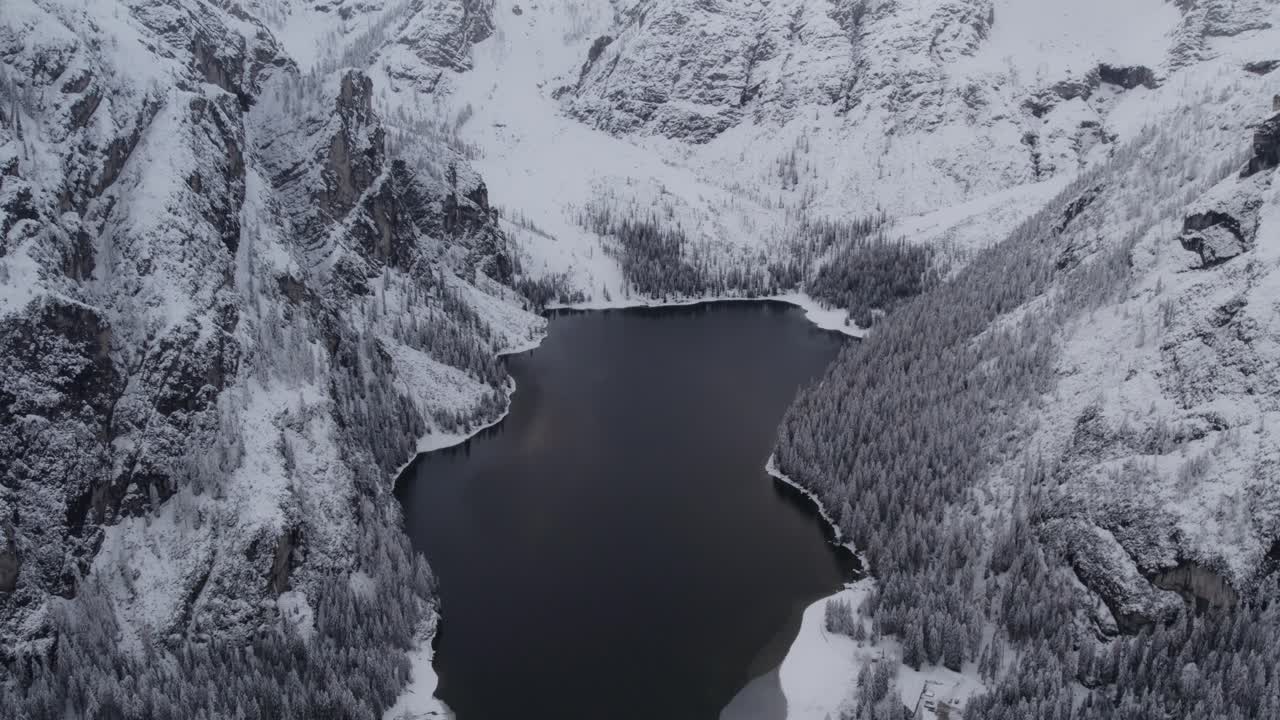 Vista aerea del Lago di Braies ghiacciato sotto cime innevate, Dolomiti, Italia