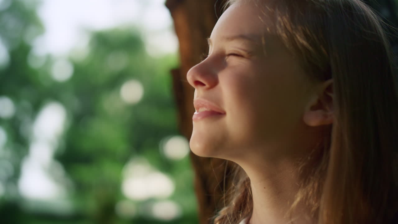 retrato de una niña soñadora del tronco del árbol delgado. niño bonito disfrutando de la cálida luz del sol solo