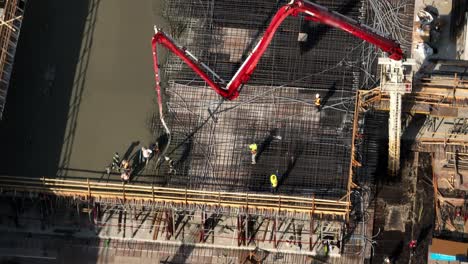 Workers-And-Boom-Arm-During-Concrete-Pouring-Activity-At-Construction-Site