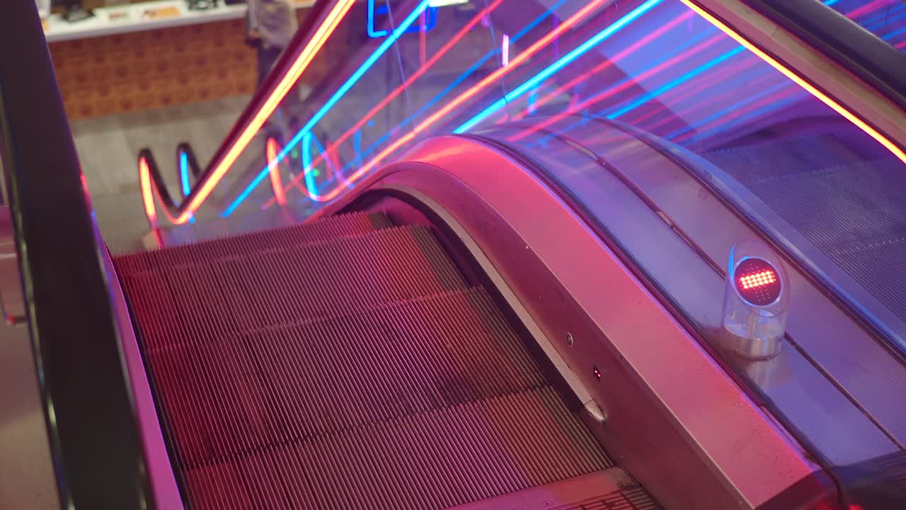 Scala mobile moderna con luci al neon in un centro commerciale