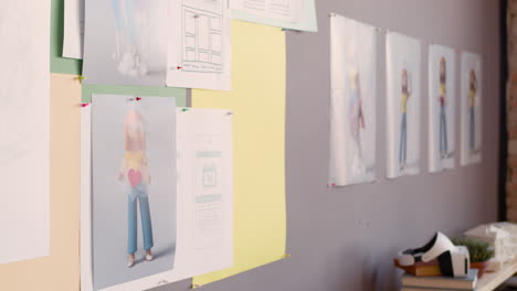 diseñadora gráfica femenina colgando un retrato a lápiz en la pared en un estudio de animación