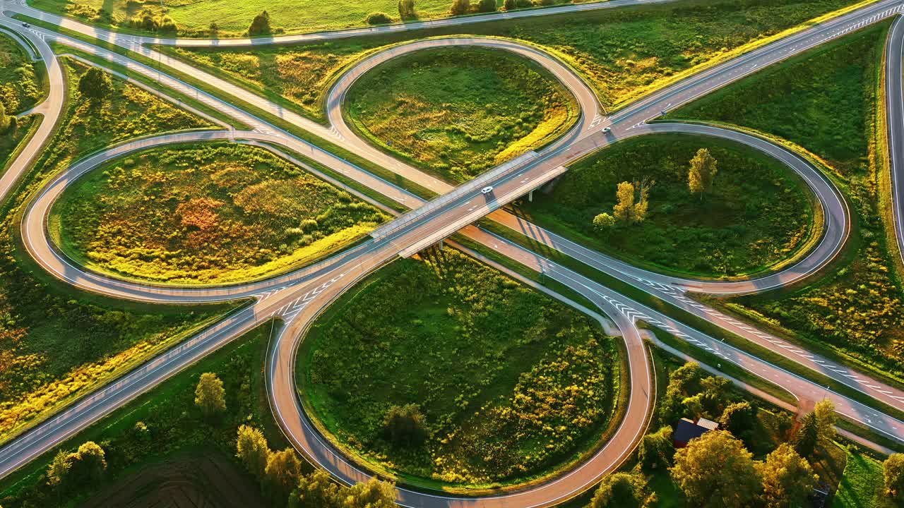 Symmetrical road interchange with curved loops in green rural area, aerial view