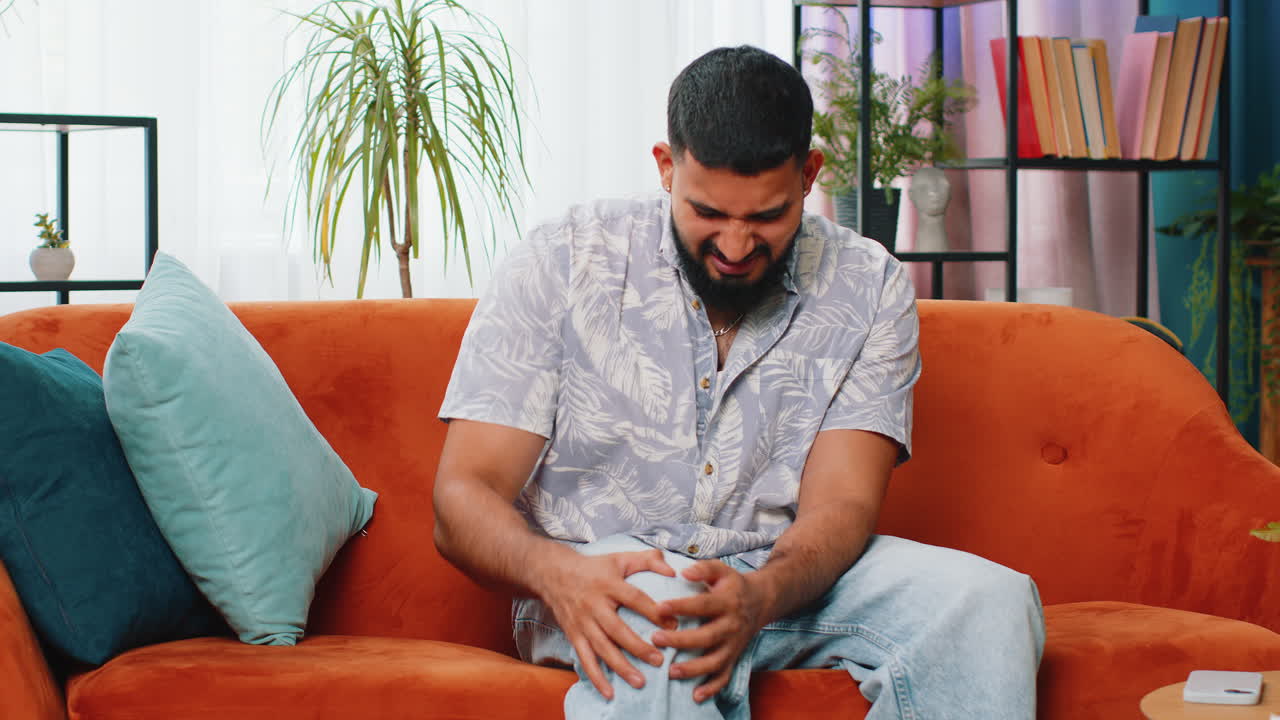 Sick Indian man suffer from painful severe knee joint ache, leg muscles illness cramps rheumatism