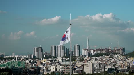 la gran bandera de la república de corea ondea en la brisa contra el horizonte de la ciudad de seúl