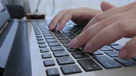 side angle of a female student's hands typing lecture notes or research on a laptop