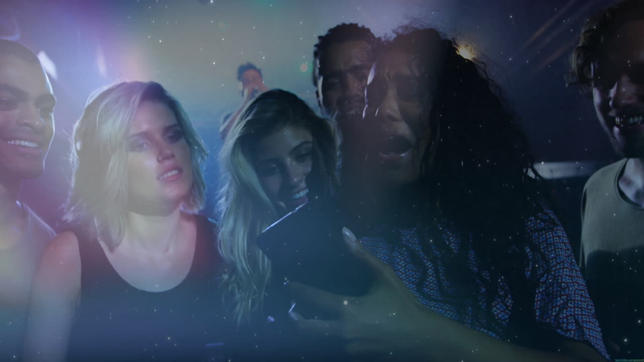 Six friends using smartphone in club showing technology with colored spotlights and light specks