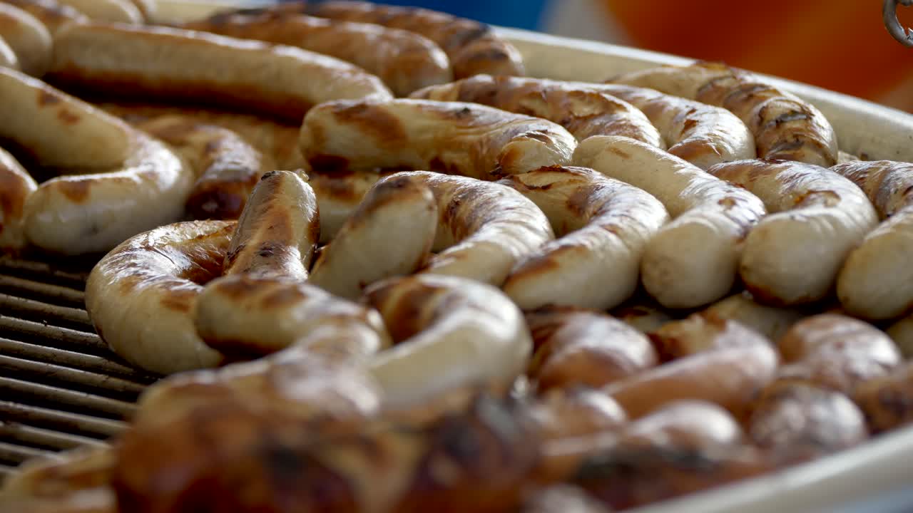 disparo de cerca que muestra varias salchichas de bratwurst fritas en la parrilla