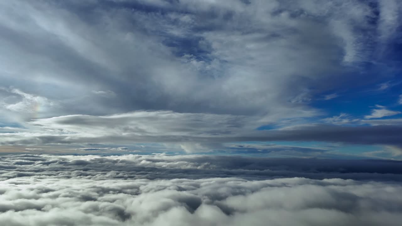 A pilot’s eye recorded from the cockpit of a jet airplane flying through multilayered clouds illuminated by the sunset light in a supersonic speed flight