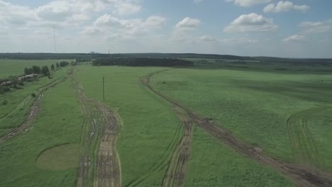 aerial view of a grassy field with dirt tracks and power lines