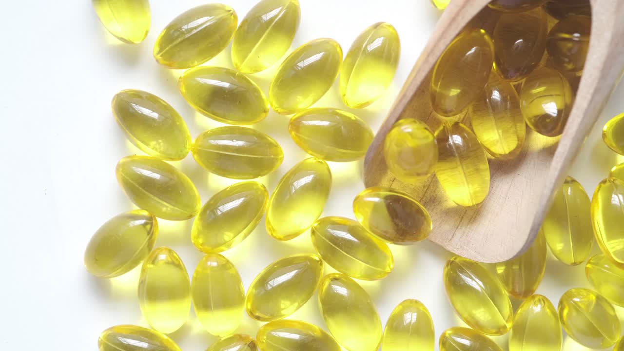 cápsulas amarillas en cuchara de madera