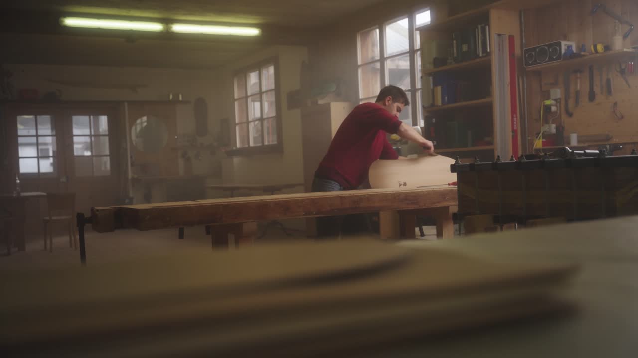 A craftsman files the edge of a wooden board
