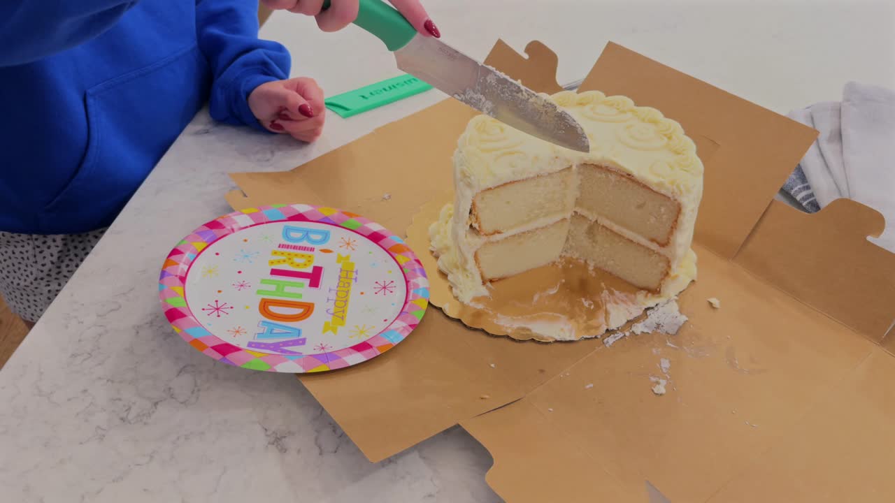 Caucasian female cutting a vanilla birthday cake
