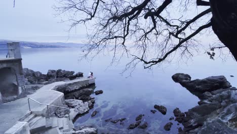 Couple-sitting-on-Sea-shore-wide-Lovran,-Opatija,-Croatia