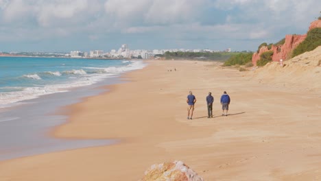 3 men walking along a beach in portugal