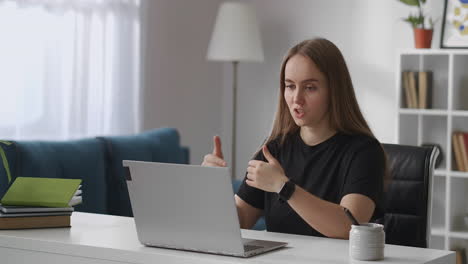 female specialist is consulting client by internet sitting at home sitting in front of laptop with web camera and talking gesticulating online consulting