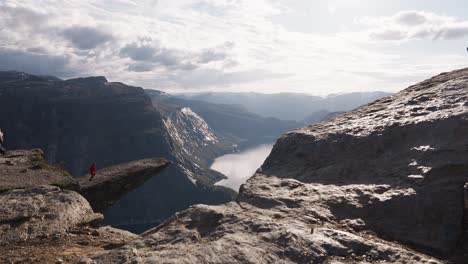 Person standing on cliff edge, dramatic Norway fjord view, sense of freedom and awe, Trolltunga