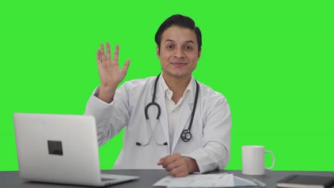 Fröhlicher-Indischer-Arzt-Winkt-Dem-Grünen-Bildschirm-Der-Kamera-Zu