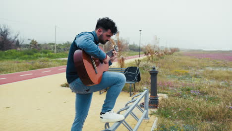 man plays the guitar facing the sea to relax