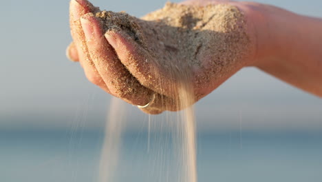 Woman-drizzling-sea-sand-through-her-fingers