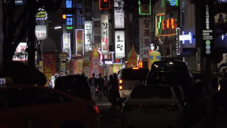 street with illuminated banners people and cars in night seoul south korea