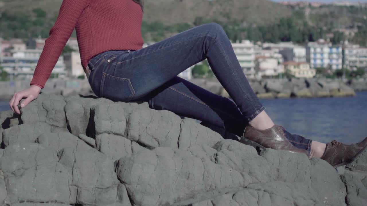 바위에 누워 선글라스를 쓴 소녀는 경치를 존경합니다