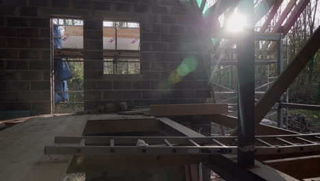pan across interior of house during first phase of build. scaffold, ladders, steel frame and block work lit by morning sunshine.