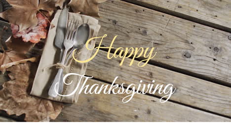 animation of happy thanksgiving text over autumn leaves and cutlery on wooden boards