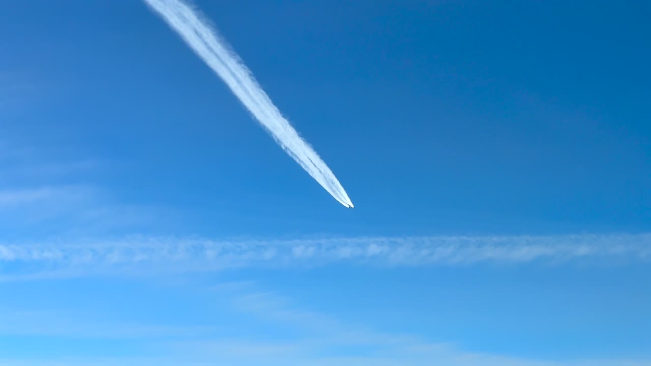 白い飛行機雲を残して青空を飛ぶジェット飛行機のコックピットからの眺め