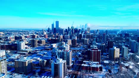 aerial drone reverse aerial flight flyover from winter capitol city of edmonton snow covered as most building are steaming thru chimney's smoke during extreme cold weather skyline skyscraper view1-2