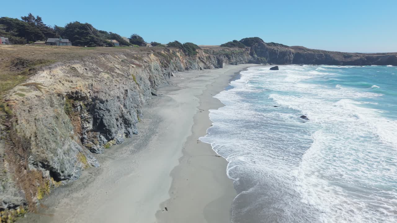 From above, Black Point Beach unfolds in dramatic beauty, with foamy tides washing over dark sands framed by the untamed Sea Ranch coastline