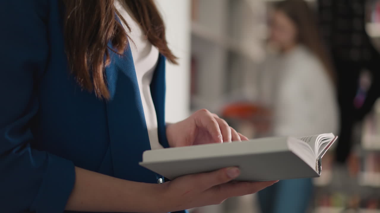 mujer da la vuelta a las páginas de un libro en una biblioteca pública. joven lector sostiene una novela abierta de pie en una librería moderna. estudiante lee literatura científica