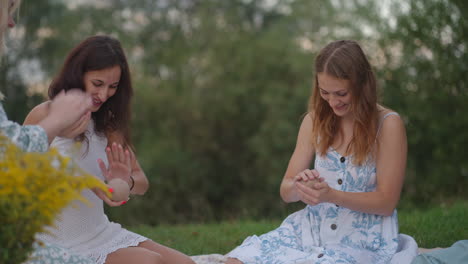 A-group-of-attractive-girls-are-engaged-in-clay-modeling-in-nature-in-a-park-in-an-open-area-talking-laughing.-Creative-classes-women's-group-classes-a-master-class.