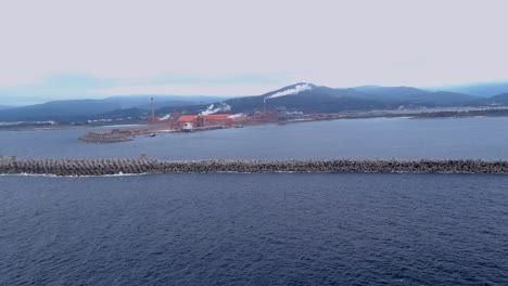 Aerial-drone-shot-over-large-ship-unloading-raw-materials-in-the-port-of-the-alumio-factory-in-San-CipriÃ¡n,-MorÃ¡s,-Xove,-Lugo,-Galicia,-Spain