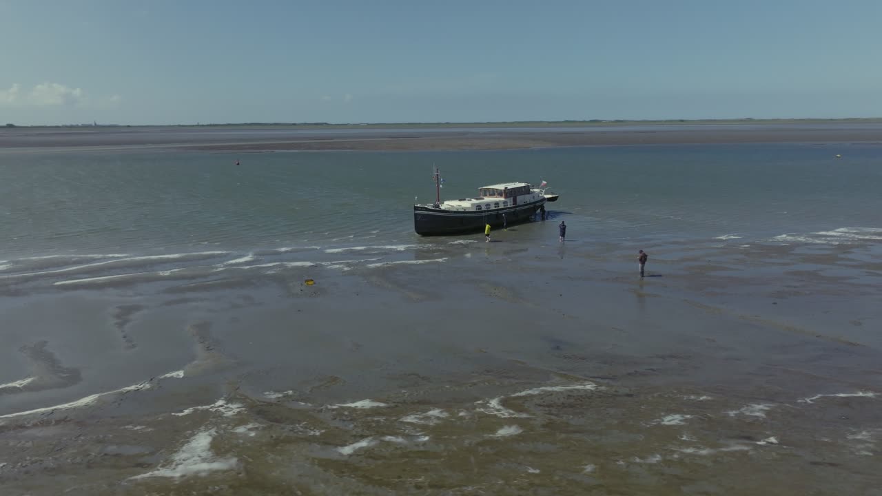 Front approach toward a grounded boat on Wadden Sea shallows at low tide; daylight, stable framing