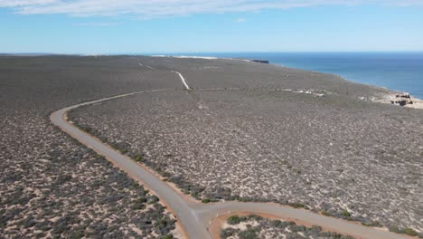 Drone-aerial-pan-up-showing-a-campervan-on-a-long-road-by-a-beautiful-ocean